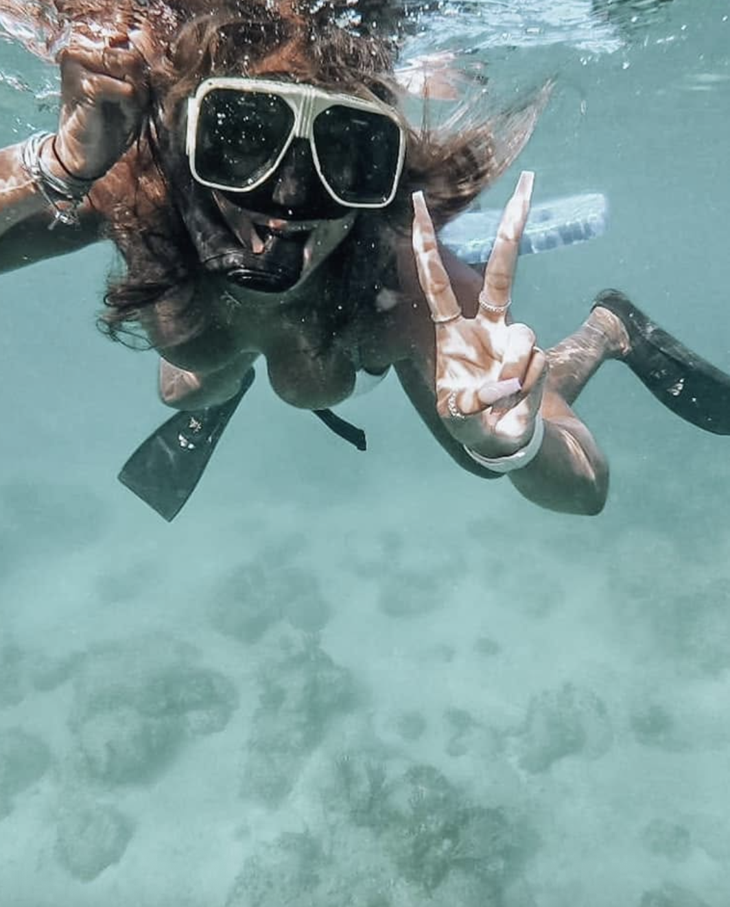 Snorkeling underwater with a peace sign